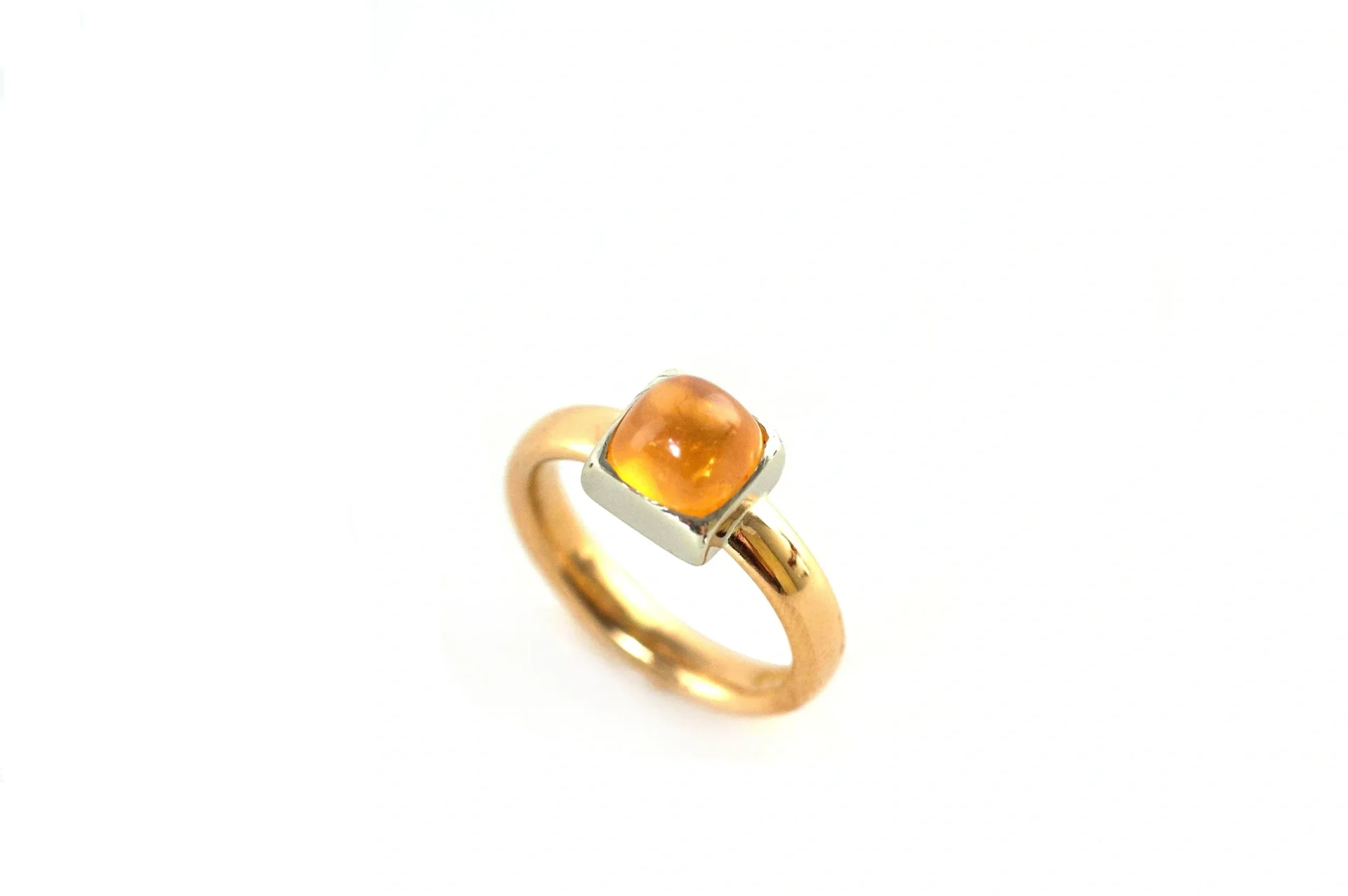 A gold ring with an orange stone on top of it.