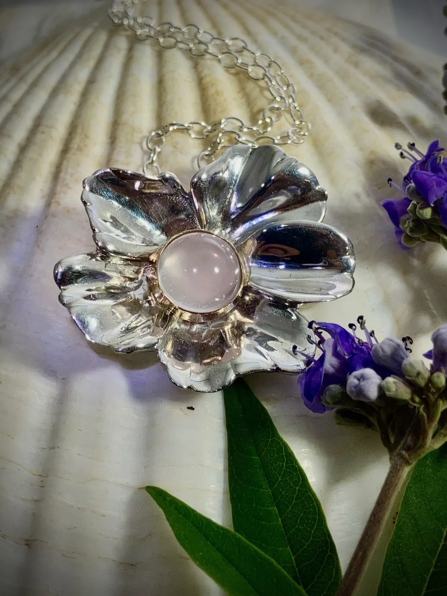 A silver flower with a rose quartz center.