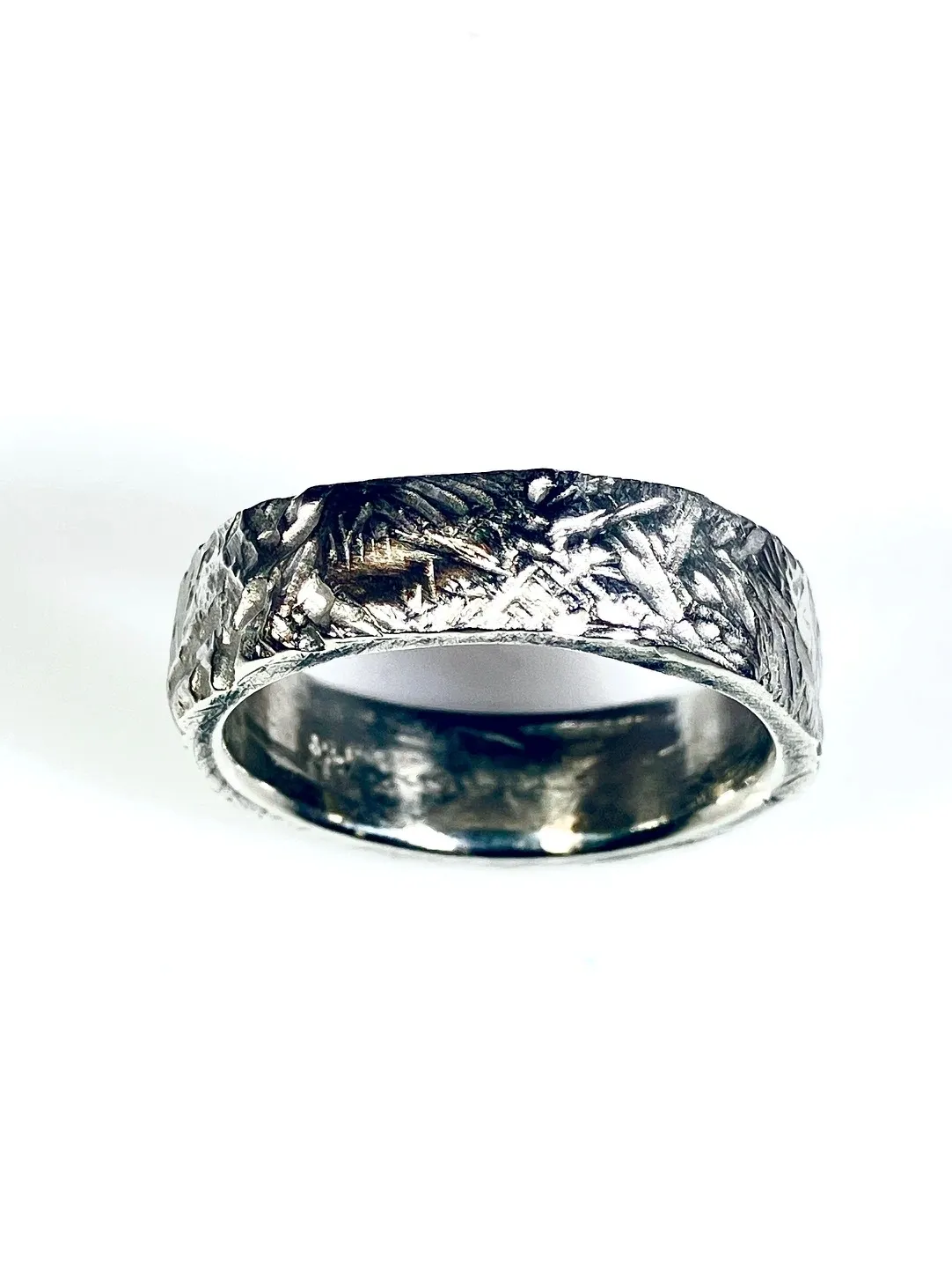 A silver ring with a metal pattern on it.