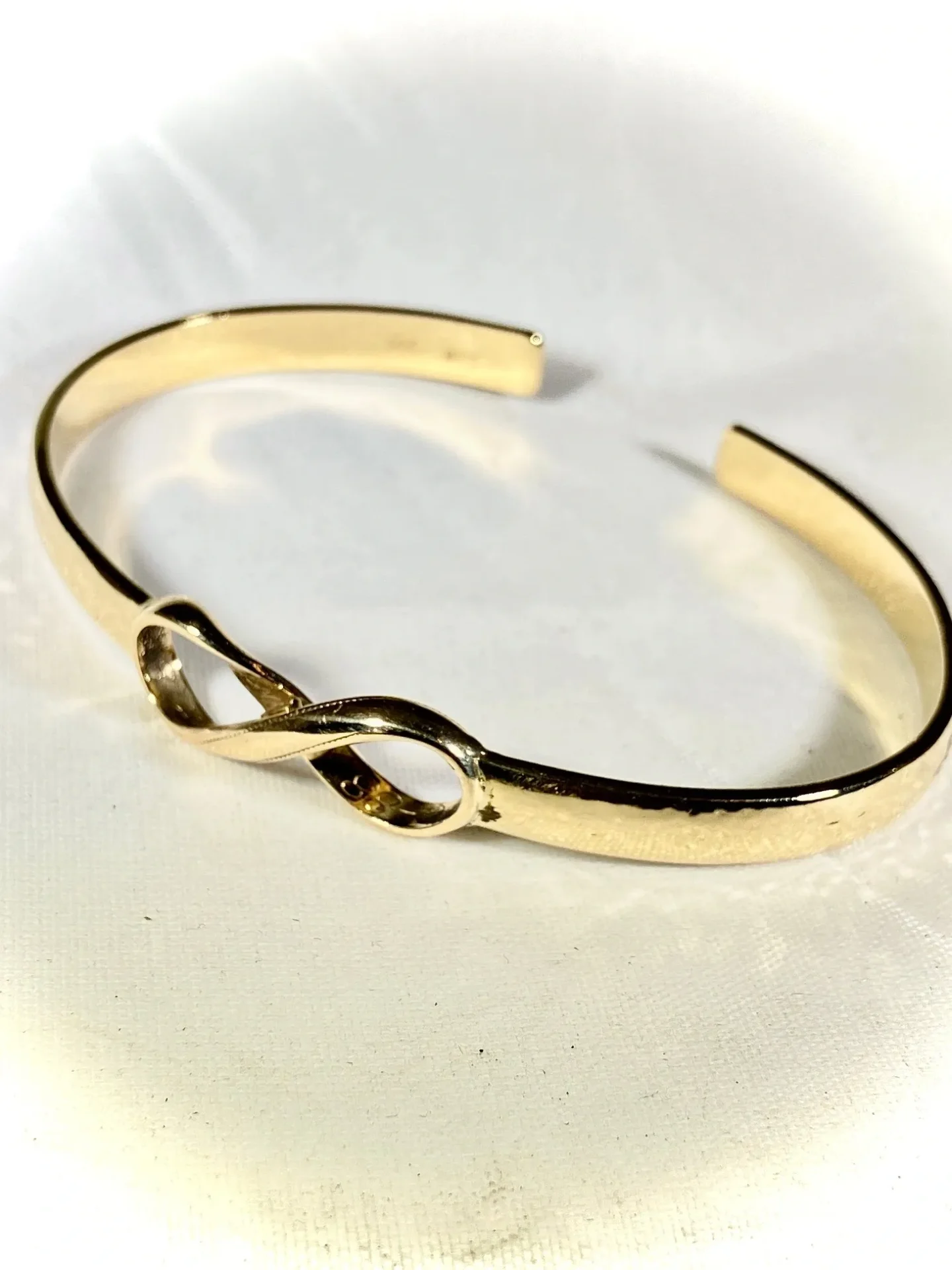 A gold bracelet with an infinity symbol on it.