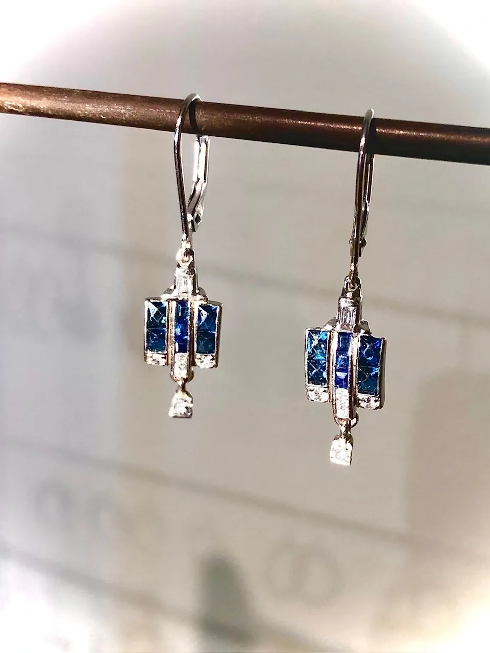 A pair of earrings hanging from a metal bar.