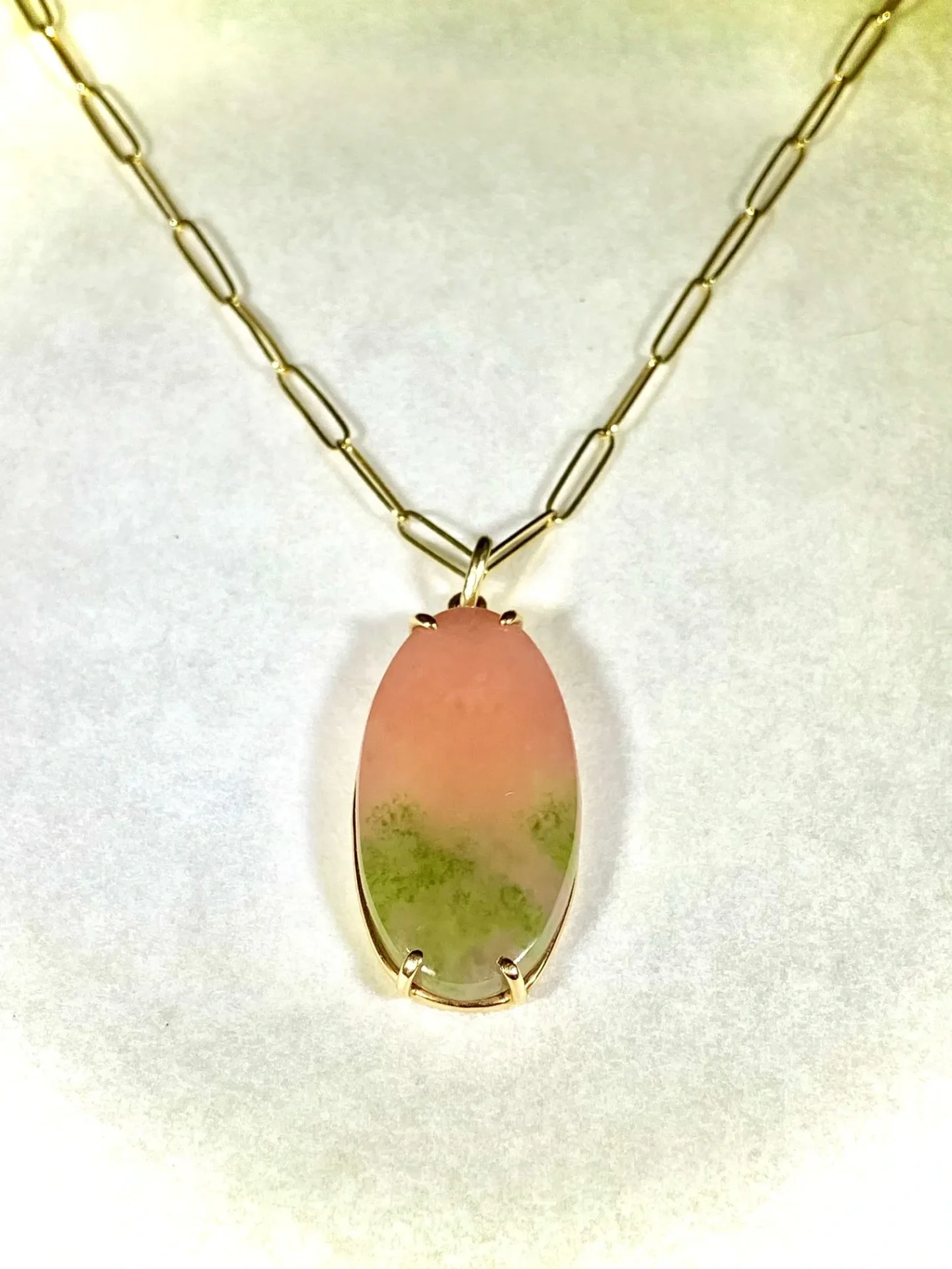 A necklace with a pink and green stone on it