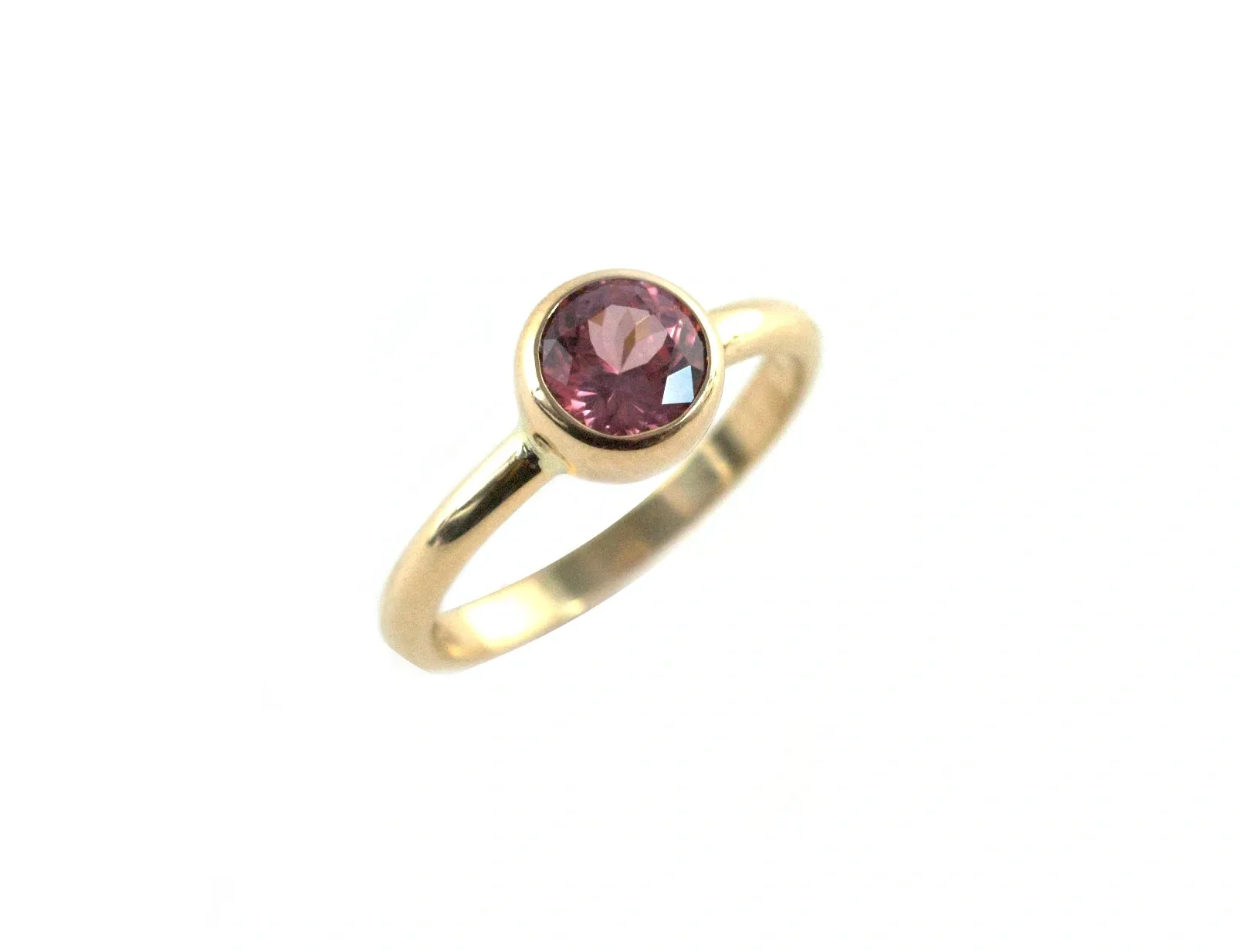 A gold ring with a pink stone on top of it.
