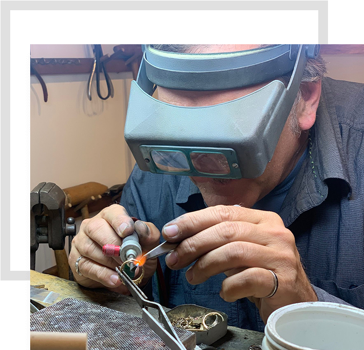 A man wearing welding goggles and holding a soldering iron.