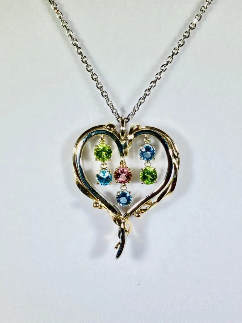 A heart shaped necklace with colored stones in it.
