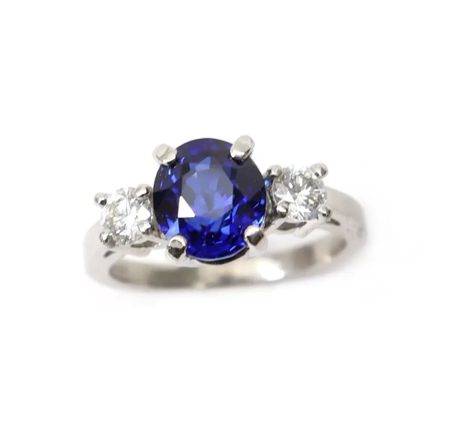 A white gold ring with a blue stone and two smaller stones.
