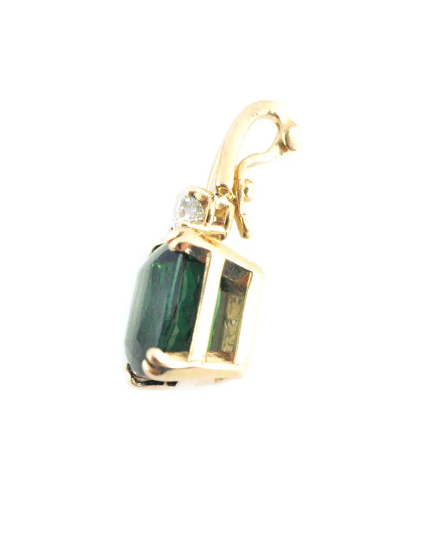A green stone is sitting on top of a gold chain.