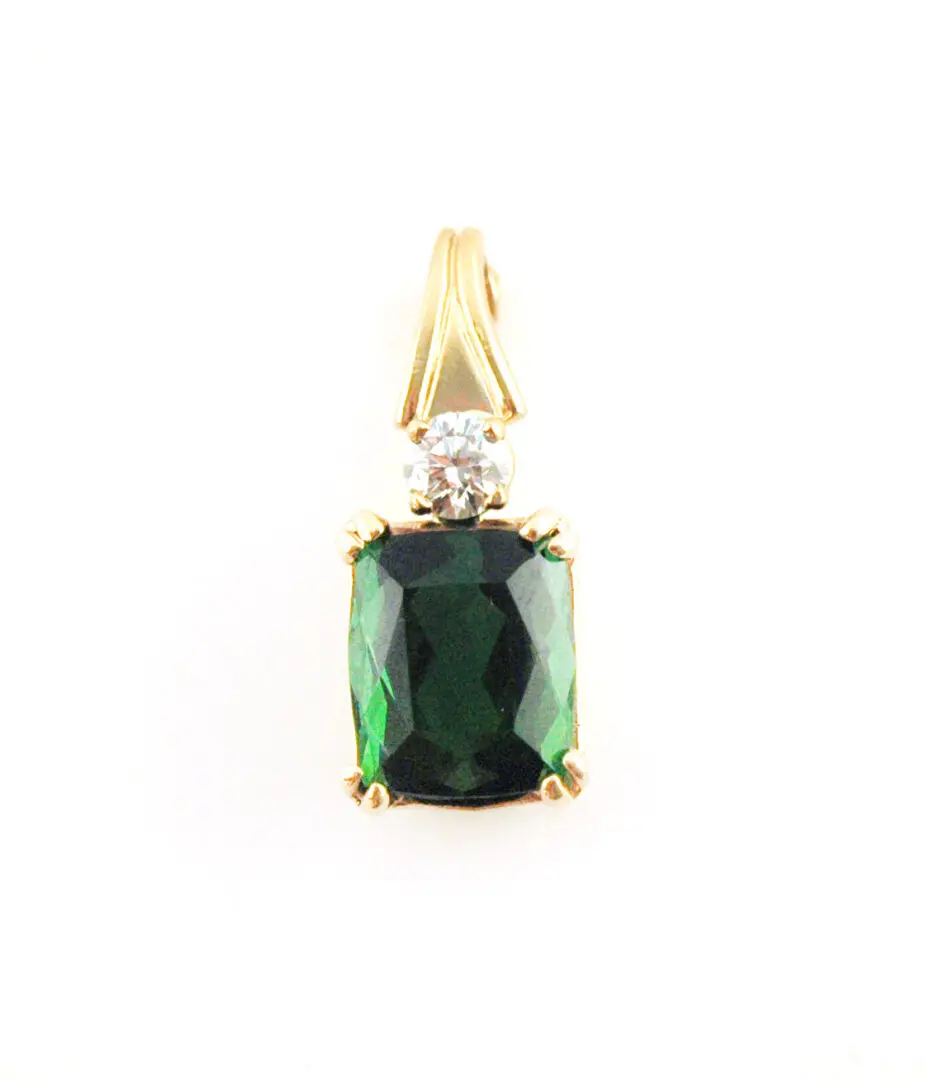 A green stone is sitting on top of a gold chain.